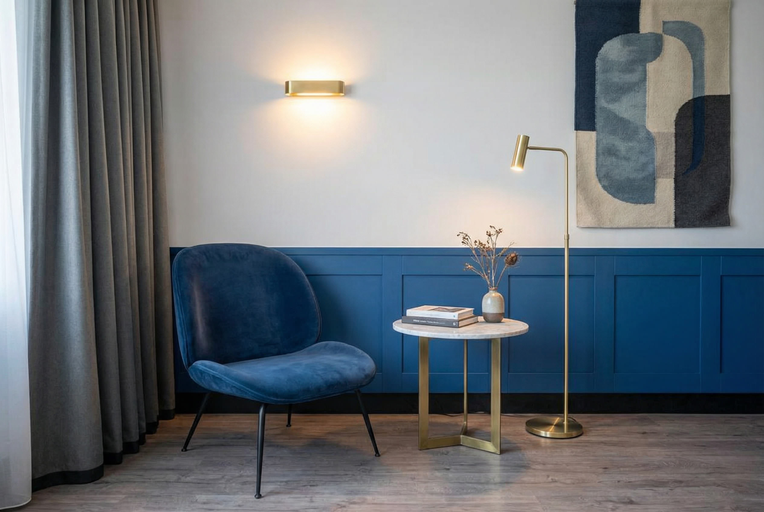 Sitzecke im Hotelzimmer mit blauem Sessel, Beistelltisch und warmem Licht
